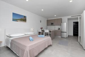 a white bedroom with a bed and a kitchen at Central Beach Apartments in Tučepi