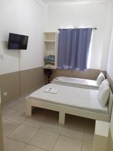 Habitación pequeña con cama y TV. en Hotel Aruba, en Curitiba