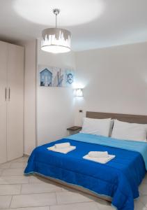 a bedroom with a blue bed and a chandelier at Casa Euripide in Syracuse