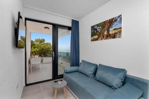 a living room with a blue couch and a large window at Central Beach Apartments in Tučepi