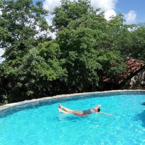 uma pessoa deitada numa piscina de água azul em Chalé do Bosque em Bonito