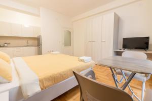een slaapkamer met een bed, een tafel en een televisie bij Comfy Apartments-Ohrid in Ohrid