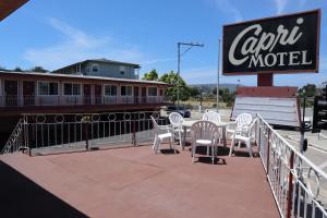 una cafetería con sillas blancas, un cartel y un tren en Capri Motel Santa Cruz Beach Boardwalk, en Santa Cruz