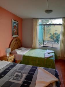 a bedroom with two beds and a large window at Waikycha Hostal in Arequipa