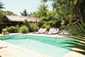 a swimming pool with two lounge chairs and a house at Musa Villas and Bungalows Gili Air in Gili Air