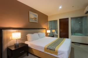 1 dormitorio con cama y mesita de noche con lámpara en Hallmark View Hotel, en Melaka