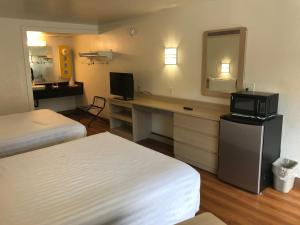 a hotel room with two beds and a desk with a microwave at Travelodge by Wyndham Fayetteville in Fayetteville