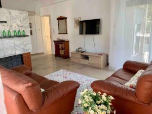 een woonkamer met twee bruine leren banken en een televisie bij Sunny Family Home By The Beach in Limassol