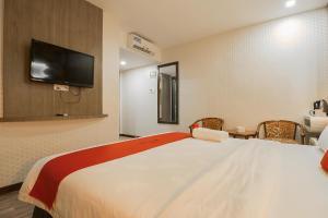 1 dormitorio con 1 cama grande y TV en la pared en Paragon Nagoya Hotel Batam en Nagoya