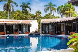 a pool at a resort with palm trees in the background at Thompson Zihuatanejo, A Beach Resort, by Hyatt in Zihuatanejo