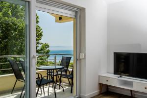 a room with a balcony with a television and a table and chairs at Apartments Mijo in Dugi Rat