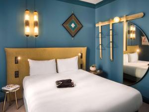 a bedroom with a large white bed with a mirror at ibis Styles Paris Nation Cours de Vincennes in Paris