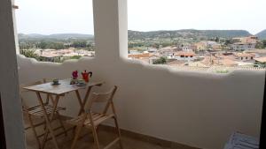 einen Tisch und Stühle in einem Zimmer mit einem großen Fenster in der Unterkunft Appartamento Su Survaju in Irgoli