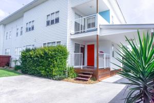 a white apartment building with a red door at Nobby Beach Holiday Village in Gold Coast