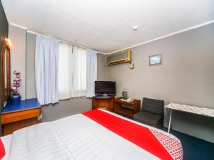 1 dormitorio con 1 cama, TV y sofá en Super OYO 1026 Hotel Lutana, en Sandakan