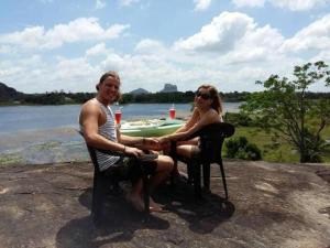 a man and a woman sitting in chairs by the water at Sigiri Lake Paradise in Sigiriya