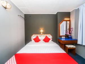 Un dormitorio con una cama roja y blanca y un espejo en Super OYO 1026 Hotel Lutana, en Sandakan