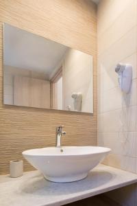 een badkamer met een witte wastafel en een spiegel bij Porfyris Studios and Apartments in Karpathos