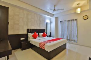 Un dormitorio con una cama grande con almohadas rojas. en Hotel Magnum Inn, en Junagadh