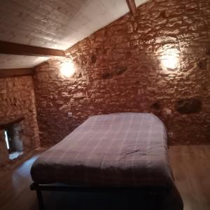 a bedroom with a bed in a stone wall at LA SAUVETAT-Yvou in Blanquefort-sur-Briolance