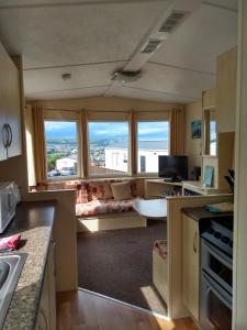 a kitchen with a living room with a large window at Swanage bay caravan in Swanage