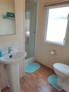 a bathroom with a sink and a toilet and a window at Swanage bay caravan in Swanage
