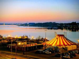 a parking lot with a tent next to a body of water at Circus Fantasia in Rostock +11 photos