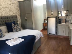 a bedroom with a king sized bed and a kitchen at Bella Blue Guesthouse in Bloemfontein