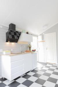 una cocina blanca con suelo a cuadros en blanco y negro en Gunnagård, en Ullared