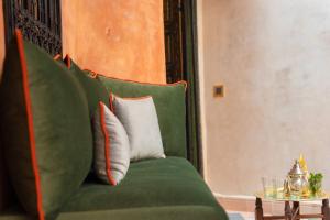 a green couch with two pillows and a table at Riad Bilkis the magic of Marrakech in Marrakesh