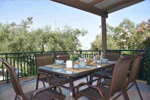 a patio table and chairs on a deck with trees at Olivella Villas by Vatos in Keri