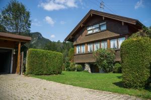 a brown house with bushes in front of a driveway at Geigers Ferienhaus in Tiefenbach bei Oberstdorf