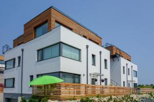 un bâtiment blanc avec un parasol vert devant lui dans l'établissement Apartament Zefir Mechelinki, à Mechelinki