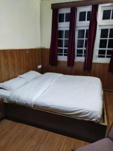 a bed in a room with two windows at Hotel Madhuban Shimla in Shimla