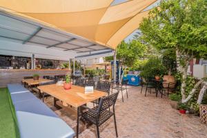 een patio met tafels, stoelen en bomen bij Oscar Villa & Studios in Alykes