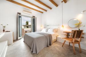 a white bedroom with a bed and a mirror at Anemomylos Residence in Naousa