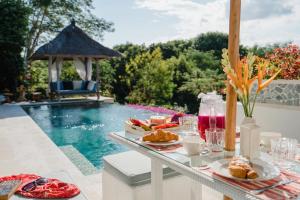 una mesa con comida y bebida junto a una piscina en Villa Nusa, en Nusa Lembongan