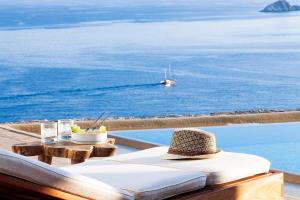 ミコノス・シティにあるAGL Luxury Villasの海の横のテーブルに座るわら帽子