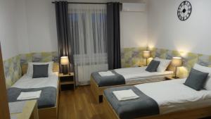 pokój hotelowy z 2 łóżkami i zegarem na ścianie w obiekcie Villa Magnolia w Oświęcimiu