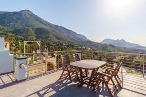 a wooden table and chairs on a balcony with mountains at Bellapais Apartments in Kyrenia