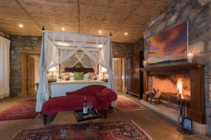 a bedroom with a bed and a fireplace at Mount Camdeboo Private Game Reserve by NEWMARK in Graaff-Reinet +165 photos