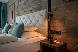 ein Schlafzimmer mit einem weißen Bett und einer Holzwand in der Unterkunft Hotel Stern in Ehrwald