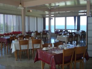 a dining room with tables and chairs in a room at Hôtel Motel du Rocher in Rivière-la-Madeleine