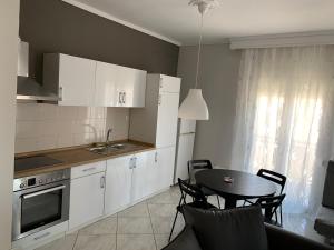 una cucina con armadi bianchi e tavolo con sedie di Apartment 30m from the sea a Salonicco