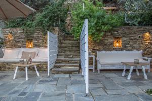 a patio with two beds and tables and a stone wall at Small Paradise in Andros