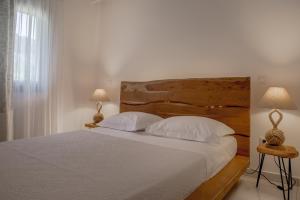 a bedroom with a bed with white sheets and two lamps at Small Paradise in Andros