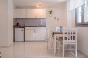 a kitchen with white cabinets and a table and chairs at Small Paradise in Andros