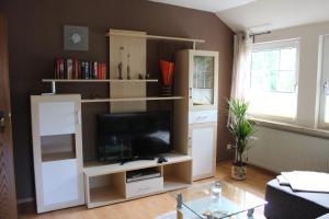 a living room with a tv in a white entertainment center at Ferienwohnung Eggers in Bispingen