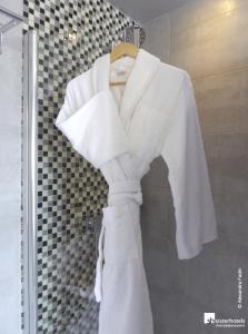 a white robe is hanging in a shower at Hôtel Bassano in Paris