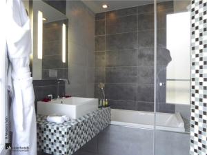 a bathroom with a tub and a sink and a shower at Hôtel Bassano in Paris